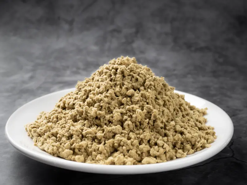 Light-yellow chopped fibre sample: a pile of light-yellow chopped fibre granules on a white plate